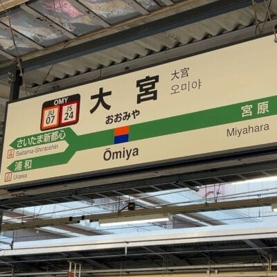 駅の案内板には、さいたま新都心と浦和行きのプラットホームの横に、日本語、韓国語、英語で大宮行きの案内が表示されている。周囲には駅の屋根構造が残されている。.