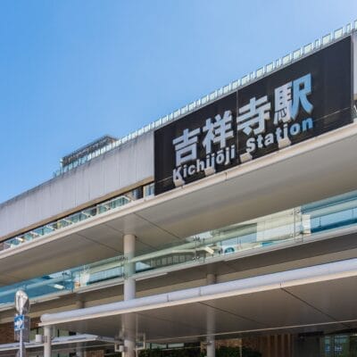 画像は晴天の下、吉祥寺駅の入口を捉えたもので、駅名が日本語と英語で大きく表示されている。すぐ近くにある英会話マンツーマン クラスは、すべての人にパーソナライズされた学習の機会を提供します。.