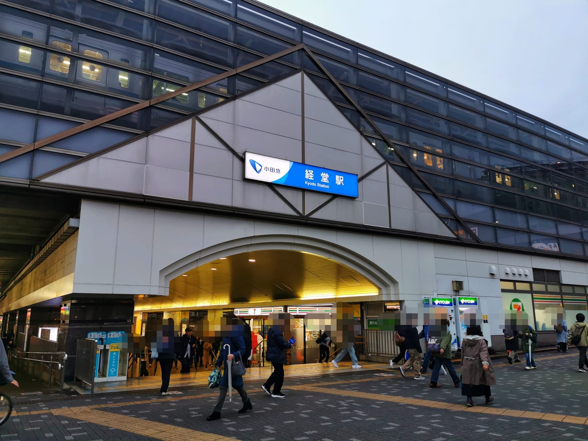 モダンなガラス張りのファサードとその上の看板が目印の京成上野駅の入口付近を歩く人々は、個別の英語レッスンを受けるために英会話スクール マンツーマンに通う経堂のにぎやかな通勤風景を思い出させます。.