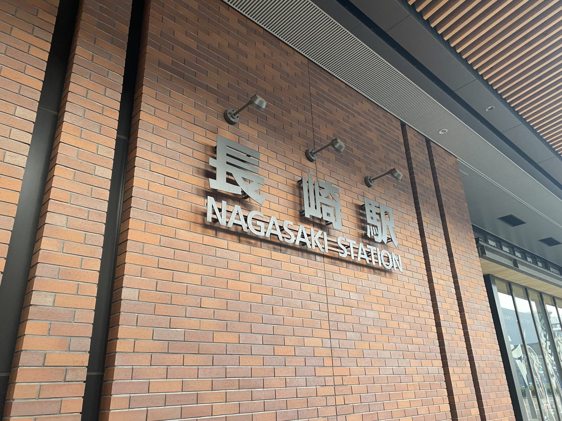 レンガ壁に屋根の庇が張り出した長崎駅入口サイン。文化の豊かさを捉えた少人数制レッスン（週1回）：月額15,000円～のプログラムに見られる古典的な優雅さを彷彿とさせます。.