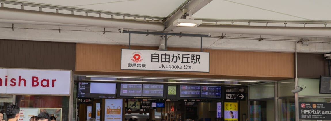 日本の自由が丘駅を出入りする人々。英会話スクールマンツーマンのさまざまな標識と上に見える案内板。.