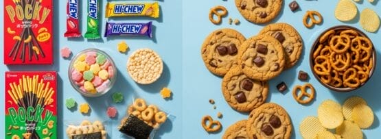 左側にポッキー、ハイチュウ、おせんべいなど、右側にチョコチップクッキー、プレッツェル、ポテトチップスなど、日本のお菓子の詰め合わせが青地に並べられている。.